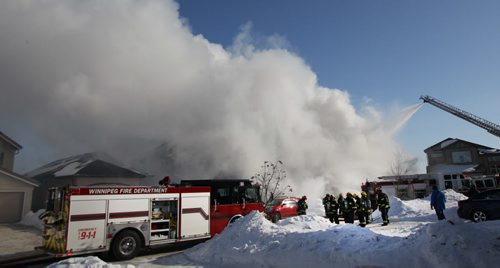 Firefighters in defensive mode stand back as aerial ladder shoots water  at a fire today on Ed Golding Bay in Transcona- The home is a total loss with officials pegging damage at $400,000-    See story- Feb 10, 2014   (JOE BRYKSA / WINNIPEG FREE PRESS)