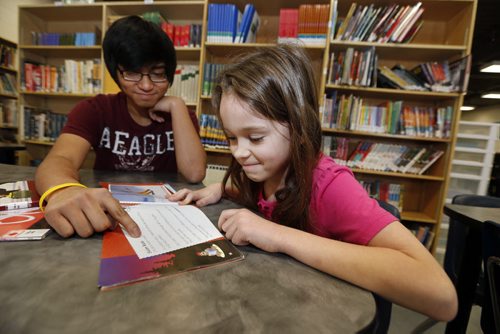 LOCAL , STUDENT BUDDIES  at Sargent Park School for story by Nick Martin on mentoring programs in schools.  LtoR  Grade 9  student Harvey Cabarlo  helps GR. 2 student Lillian Hutchinson  with her reading skills .   FEB. 10 2014 / KEN GIGLIOTTI / WINNIPEG FREE PRESS