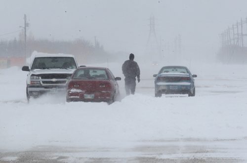 A passerby helps free a car from being stuck in a snow drift on Wilkes Ave. as high winds create  snow drifts across many Manitoba highways and  roads  on Tuesday afternoon.  Weather Standup Ruth Bonneville / Winnipeg Free Press