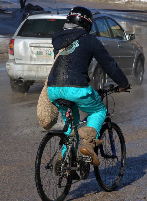 Messy Ride- A cyclist make her way down Sherbrook St in Winnipeg Tuesday afternoon- Balmy temperatures in town have hit near zero causing melting on city streets-standup photo- Feb 18, 2014   (JOE BRYKSA / WINNIPEG FREE PRESS)