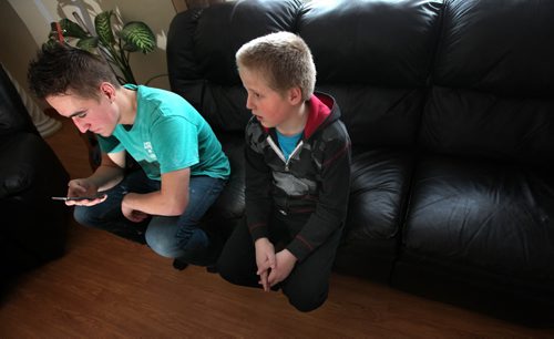 17 yr old Sam keeps an eye on his smart phone while brother Jonathan stays close. See Bill Redecopp story AND Video re: 13 orphaned kids adopted by their Uncle and Aunt. February 20, 2014 - (Phil Hossack / Winnipeg Free Press)
