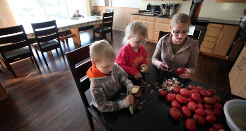 L-R - Nathan(7), Nelly (5) and Hanna (14) peel potatoes for their supper Thursday. See Bill Redecopp story AND Video re: 13 orphaned kids adopted by their Uncle and Aunt. February 20, 2014 - (Phil Hossack / Winnipeg Free Press)