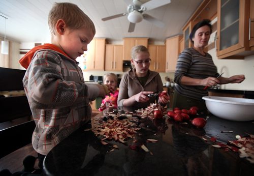 7 yr old Nathan helps Hanna (14) and his mom Lina peel potatoes for the family supper Thursday. See Bill Redecopp story AND Video re: 13 orphaned kids adopted by their Uncle and Aunt. February 20, 2014 - (Phil Hossack / Winnipeg Free Press)
