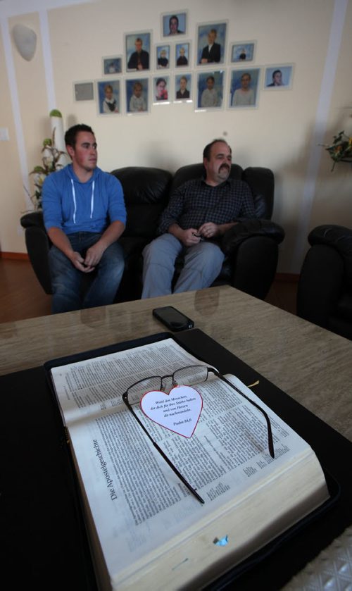 22 yr old David sits with his father Jacob framed by portraits of all the DIK children and the family bible. See Bill Redecopp story AND Video re: 13 orphaned kids adopted by their Uncle and Aunt. February 20, 2014 - (Phil Hossack / Winnipeg Free Press)