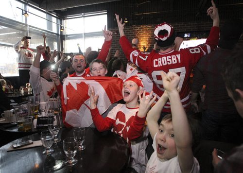 Little fans Jackson Zuk (holding flag), 8, Jack Derrett (centre), 9, and Grey Davidson (right), 7, at the Confusion Bar & Grill cheer after Canada wins the Olympic Men's Hockey Gold medal game against Sweden 3-0 Sunday morning. 140223 - Sunday, February 23, 2014 -  (MIKE DEAL / WINNIPEG FREE PRESS)