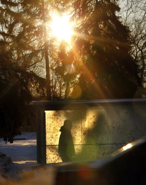 A transit rider takes shelter on Main St. as the sun rises on another cold -25C Monday morning. Wayne Glowacki / Winnipeg Free Press Feb. 24   2014