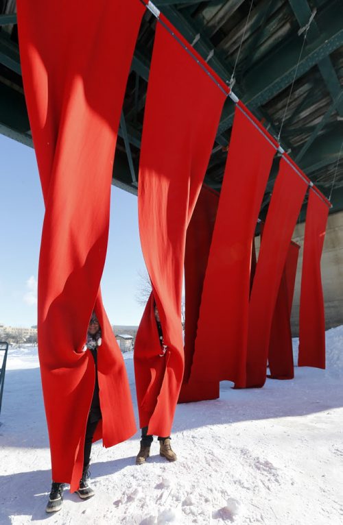 Stdup- Gimme Shelter LtoR Michelle  Alagar  and Ben Javate take shelter from the freezing  cold using the red felt wool of  the Red Blanket by  Workshop Architecture Inc. Warming Hut entry at the Forks on the Assiniboine River    FEB. 24 2014 / KEN GIGLIOTTI / WINNIPEG FREE PRESS