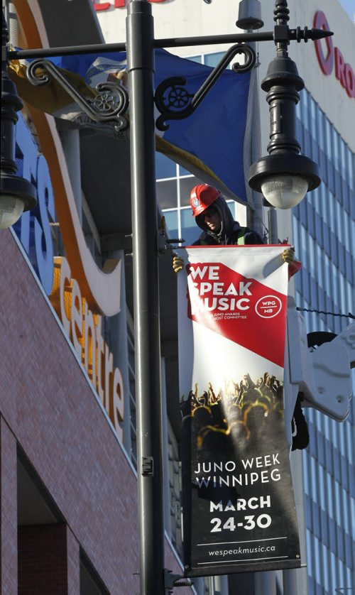 Prior to the  news conference to announce the JUNO  Week details at the Metropolitan Entertainment Centre Tuesday morning Shane Goertzen attaches the first JUNO banner on Portage Ave. at Donald St. Wayne Glowacki / Winnipeg Free Press Feb. 25   201