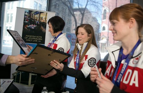 Olympic curling champions Jill Officer (left) Kaitlyn Lawes and Dawn McEwen receive framed prints of the Winnipeg Free Press front page of their gold medal win at the Sochi 2014 Winter Olympics. The three Team Jones members visited with fans at the Free Press News Caf¾© Tuesday. 140225 - Tuesday, {month name} 25, 2014 - (Melissa Tait / Winnipeg Free Press)