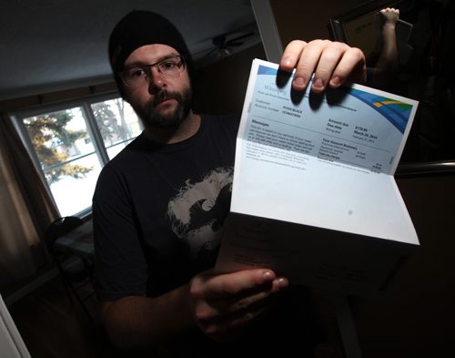 Forced to keep water running through a temproary hose between his house and a neighbors he brandishes the newly received (high) water bill. See story.. February 26, 2014 - (Phil Hossack / Winnipeg Free Press)