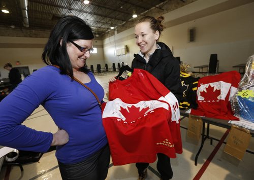 Left ,  Jocelyne Larocque  with jersies signed  by Men's and Women's , Gold Medal winning  team  from Canada's Gold Medal  performances during the  Sochi Olympics  .In pic with her  soon to be sister inlaw Shawnda  Gubersky (left)  . Larocque   brought the jersies  to be auctioned off at her sisters wedding social  tonight (Friday night)   at Crescentwood Community Centre on Corydon Avenue afternoon .Both were   helping set up for her sister's wedding social. She'll have  two signed jerseys  and a third black team Canada jersey for auction. ... FEB. 28 2014 / KEN GIGLIOTTI / WINNIPEG FREE PRESS