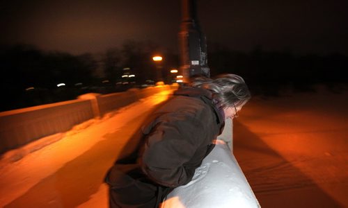 Alden Wiebe peers over the Assinaboine Park pedestrian bridge Monday night. He jumped off the bridge in a desperate attempt to escape his problems while homeless in 2012. See Randy Turner story. March 3, 2014 - (Phil Hossack / Winnipeg Free Press)