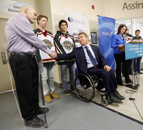 Rick Hansen shakes hands with (left) Scott Coates  who lives with a spinal cord injury he got 22 years ago , he has earned two masters degrees  and coached 5 AAA hockey Championship s  and was with members of his AAA Wpg Warriors   at the  newser with  Minister Erin Selby  The Mb. Gov. Is investing $3 million   over 5 years  with the Rick Hansen Foundation , Manitoba chapter of   The Canadian Paraplegic Ass.  To help people with spinal cord injuries recover  and return to their homes  and jobs . Story by Larry Kusch  Mar. 4 2014 / KEN GIGLIOTTI / WINNIPEG FREE PRESS
