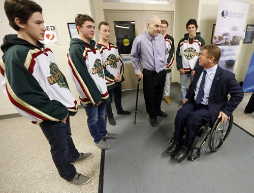 Rick Hansen shakes meets  with  (centre standing ) Scott Coates  who lives with a spinal cord injury he got 22 years ago , he has earned two masters degrees   and coached 5 AAA hockey Championship s  and was with members of his AAA Wpg Warriors   at the  newser with  Minister Erin Selby  The Mb. Gov. Is investing $3 million   over 5 years  with the Rick Hansen Foundation , Manitoba chapter of   The Canadian Paraplegic Ass.  To help people with spinal cord injuries recover  and return to their homes  and jobs . Story by Larry Kusch  Mar. 4 2014 / KEN GIGLIOTTI / WINNIPEG FREE PRESS