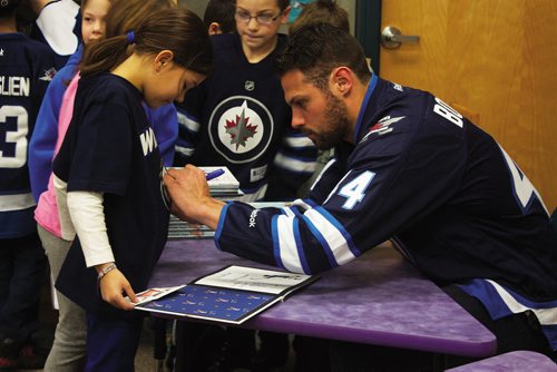 Canstar Community News Feb. 25/14 - Winnipeg Jets defenceman Zach Bogosian signs a young fan's shirt at Prince Edward School on Feb. 25. Bogosian and centre Mark Scheifele attended the I Love to Read Month event through the team's Reading Takes Flight program. (DAN FALLOON/CANSTAR COMMUNITY NEWS/HERALD)