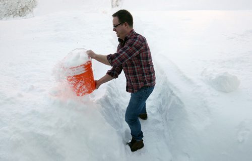 Brent Sayles scoops snow to bring into their bathroom to melt for use as toilet flushing water- The Sayles are one of over 700 families in Winnipeg that are coping with no water because of frozen water lines-    See Aldo Santin story- March 07, 2014   (JOE BRYKSA / WINNIPEG FREE PRESS)