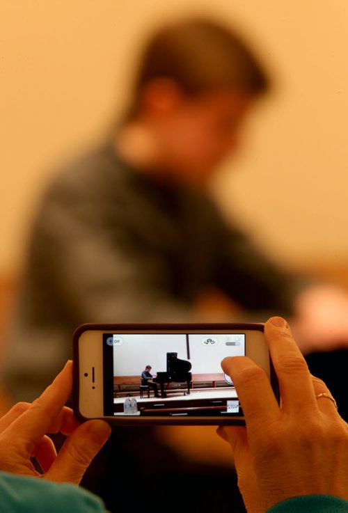 An audience member films Callum Goulet-Kilgour, 12, as he performs in the Grade 7 Canadian Composers section of the Winnipeg Music Festival at the Sterling Mennonite Fellowship, Saturday, March 8, 2014. (TREVOR HAGAN/WINNIPEG FREE PRESS)