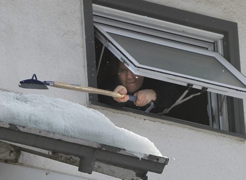 Thom Hiebert chips away at a ice dam from his third floor window of his home on Grosvenor Avenue  Monday.     Wayne Glowacki / Winnipeg Free Press March 10   2014