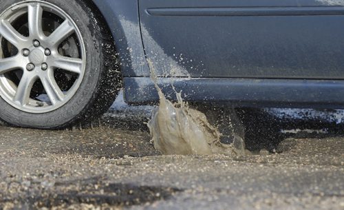 Car hits a pothole on Keewatin St. near Logan Ave. Monday.  For infrastructure story  Wayne Glowacki / Winnipeg Free Press March 10   2014