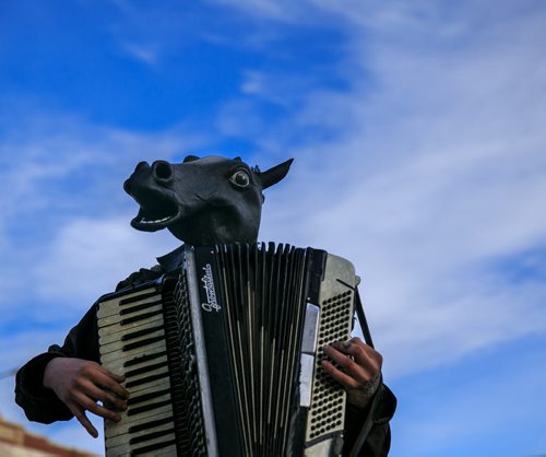 A busker named Blaine, beside his dog Ranger, plays an accordion while wearing a horse head outside the MLCC in Osborne Village Monday evening. 140310 - Monday, March 10, 2014 - (Melissa Tait / Winnipeg Free Press)