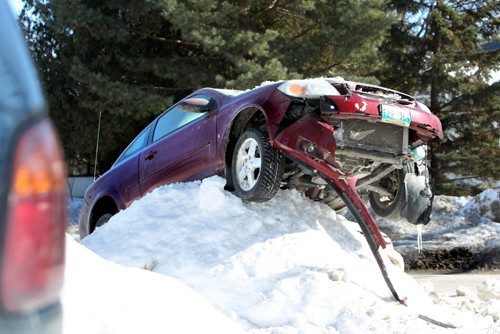 A car precariously rests high on a snowbank on St Vital Rd. as Police Investigate the scene of a two car MVA Saturday.  St. Vital Rd is closed to vehicle traffic between St. Mary's Rd and Dunkirk Drive at time of photo (3:30pm).  No information as to what caused the accident.  There was a Police Check Stop vehicle at the scene.    Standup photo  March 15, 2014  Ruth Bonneville / Winnipeg Free Press
