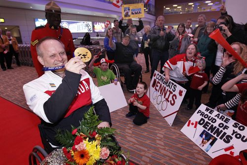 March 18, 2014 - 140318  -  Dennis Thiessen, gold medal curling Paralympian, shows off his medal as he is greeted by family and friends as he arrives at Winnipeg Airport Tuesday, March 18, 2014. John Woods / Winnipeg Free Press