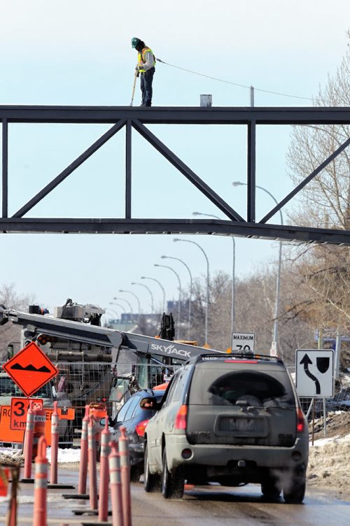 Drivers making their way along Grant Avenue past the Canadian Mennonite University got to watch crews work high over their heads on the skywalk being built. 140319 - March 19, 2014 MIKE DEAL / WINNIPEG FREE PRESS