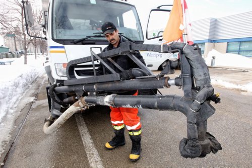 Equipment Operator, Walter Galego, inspects one of the road repair trucks that are being readied for the streets. These remote operated trucks allow the driver or passenger to operate the pothole filling apparatus from inside the cab. They also need to be used in temperatures above freezing as the oil based emulsion that is added to the pebbles thickens or freezes too quickly while in the pipes along the extension arm.  140319 - March 19, 2014 MIKE DEAL / WINNIPEG FREE PRESS