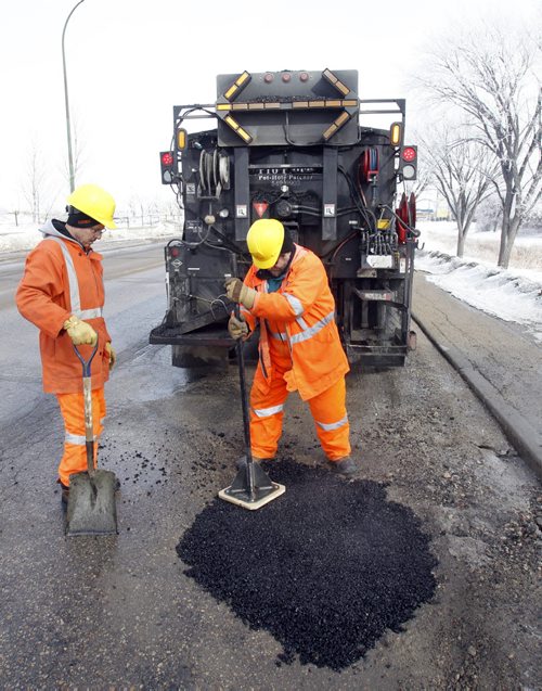 Saturday Special. City crews apply "cold mix" from the Transporter  into a pothole on Empress St. on a day with  below freezing temperatures and then the cold mix is pounded flat to patch the hole.    Kevin Rollason story Wayne Glowacki / Winnipeg Free Press March 20   2014