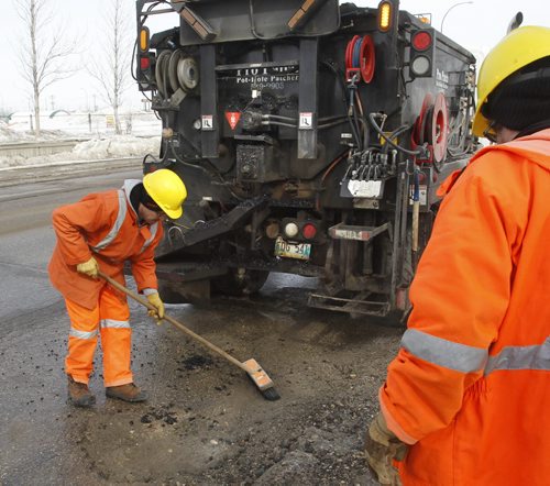 Saturday Special. City crew sweep clean pot hole before they apply "cold mix" from the Transporter  into a pothole on Empress St. on a day with  below freezing temperatures.     Kevin Rollason story Wayne Glowacki / Winnipeg Free Press March 20   2014
