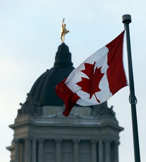 Stdup . Flags at the Manitoba Legislature  are whipped up  by high winds 50 to &0 kph  feels like minus 21 ,Frozen  , the warm weather on the first day of spring Thursday caused a  qiuck melt , but returning arctic air  and high wind Friday  casued a quicker freeze on icy streets . Mar. 21 2014 / KEN GIGLIOTTI / WINNIPEG FREE PRESS