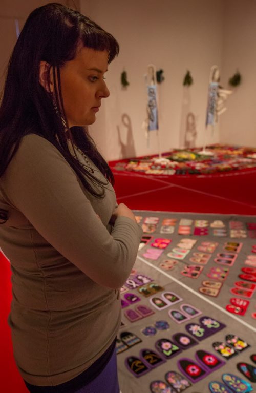 Erin Konsmo, the national collective youth coordinator and media contact for the Walking With Our Sisters commemorative art installation project, spends time with the installation at the Urban Shaman Gallery in Winnipeg on Friday, March 21, 2014. The project seeks to honour to the lives of missing and murdered Indigenous women and girls by displaying over 1760 donated moccasin tops, or vamps, each of which are intentionally not sewn into moccasins, and represent the unfinished lives of Indigenous missing and murdered women and girls. The project is currently booked to tour more than 30 locations across North America over the next six years, into the year 2019. (Photo by Crystal Schick/Winnipeg Free Press)
