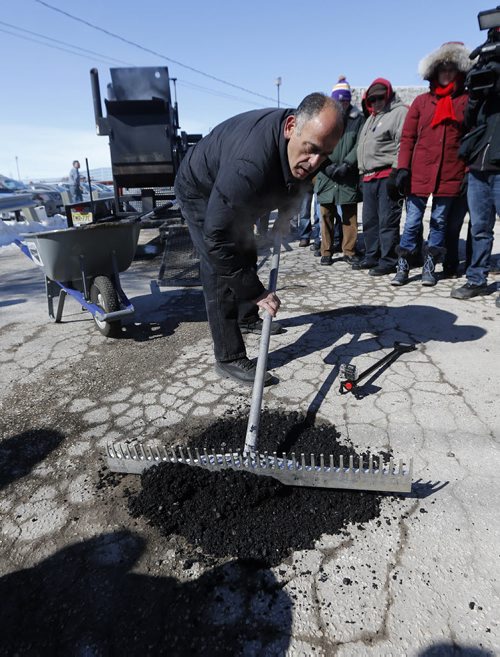 Pot Hole Repair -  Thunder Bird Restaurant,  Pellet Patch sales rep Saverio Marra director of sales  spreads  mixture  as he demonstrates  pot hole reapair technology using asphalt and rubber     and  the effectiveness of a hot-mix-asphalt patching compound that had good results in Flint, Mich. Mar. 21 2014 / KEN GIGLIOTTI / WINNIPEG FREE PRESS