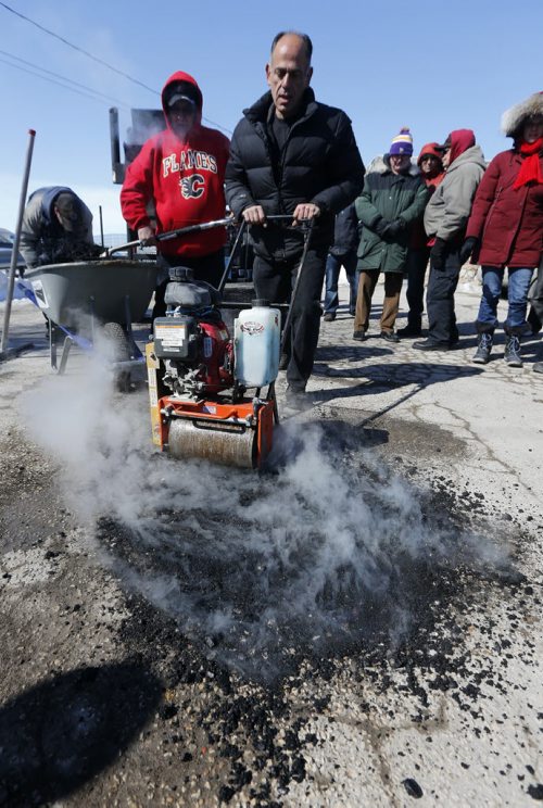 Pot Hole Repair -  Thunder Bird Restaurant, Pellet Patch sales rep Saverio Marra director of sales demonstrates  uses roller to smooth hot mixture into pot hole, pot hole reapair technology using asphalt and rubber     and  the effectiveness of a hot-mix-asphalt patching compound that had good results in Flint, Mich. Mar. 21 2014 / KEN GIGLIOTTI / WINNIPEG FREE PRESS