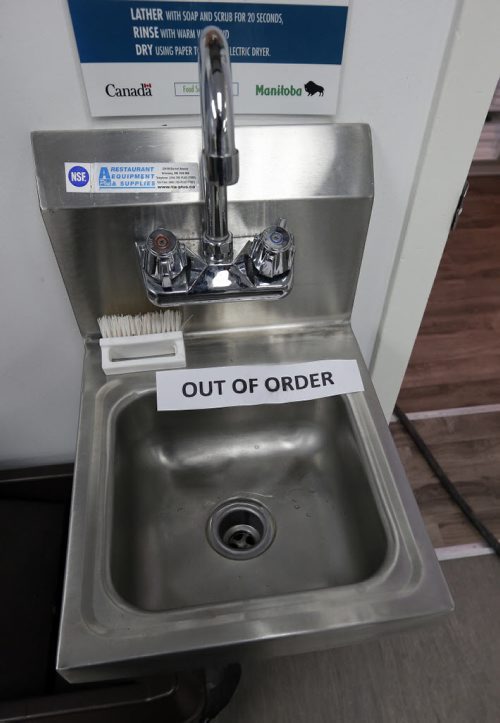Out of order sign on sink, water line frozen to the shop - Melting Water Pipes - Working in a tight subfloor crawl space beneath the shop a crew from Tractus Projects is at a chocolate shop on Provencher, Chocolatier Constance Popp, whose pipes are frozen. Tractus is the firm who jerry-rigged a thawing machine and restored water last week at an Evanson Street house. TheyÄôre trying to do the same thing for this business. Pic of  crew working and of owner Constance Menzies in photos Mar. 24 2014 / KEN GIGLIOTTI / WINNIPEG FREE PRESS