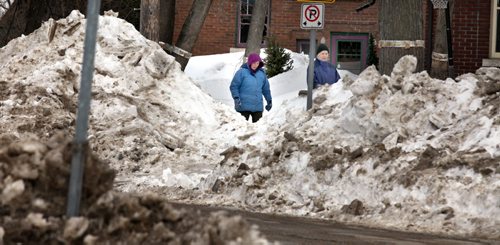 Dwarfed by piles of snow eft over from winter, pedestrians make their way along Palmerston Ave. Prequel for Turner tale re: driving south to find spring. March 26, 2014 - (Phil Hossack / Winnipeg Free Press)
