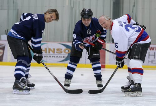 Jay Bodner, centre, drops the pucks for Jim Cuddy, left, captain for the Rockers, and Mark Napier, captain for the NHLers, as they pretend to face-off at their practice for the Juno Cup at the MTS Iceplex in Winnipeg on Thursday, March 27, 2014. (Photo by Crystal Schick/Winnipeg Free Press)