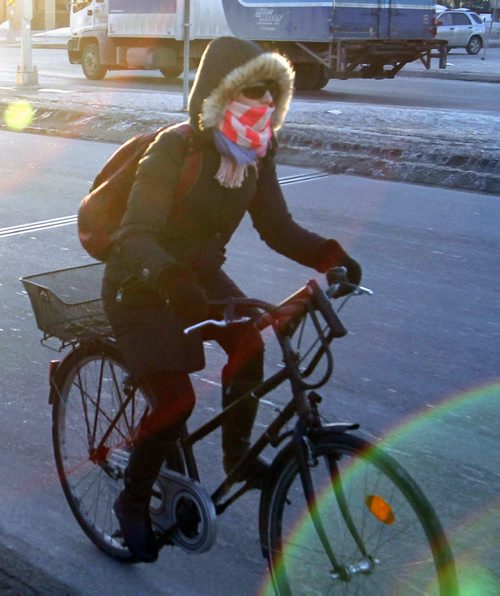 A cyclist is dressed for the -16C temperature Friday morning while travelling over the Esplanade Riel .   For weather story.  Wayne Glowacki / Winnipeg Free Press March 28   2014