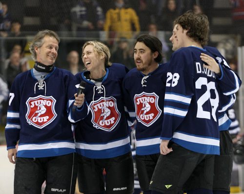 Canadian rock star Jim Cuddy, left has a laugh with Amanda Rheaume as they and others on Team Rockers sing Oh Canada before play Friday night against Team NHL Greats at the 11th annual Juno Cup at MTS iceplex Friday night-   Juno Standup- Mar 28, 2014   (JOE BRYKSA / WINNIPEG FREE PRESS)