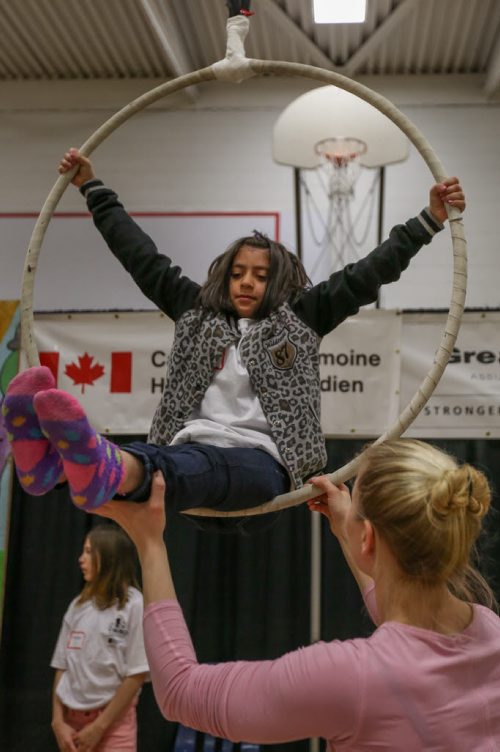 Farkhunda Haroon, 9, top centre, learns the hoop from Kim Craig, right, an aerialist from Calgary's Street Circus Show, at the 17th annual Circus and Magic Partnership (C.A.M.P) at Gordon Bell High School in Winnipeg on Tuesday, April 1, 2014. C.A.M.P is an artistic intervention project for at-risk kids, spearheaded by the Winnipeg International Children's Festival . (Photo by Crystal Schick/Winnipeg Free Press)