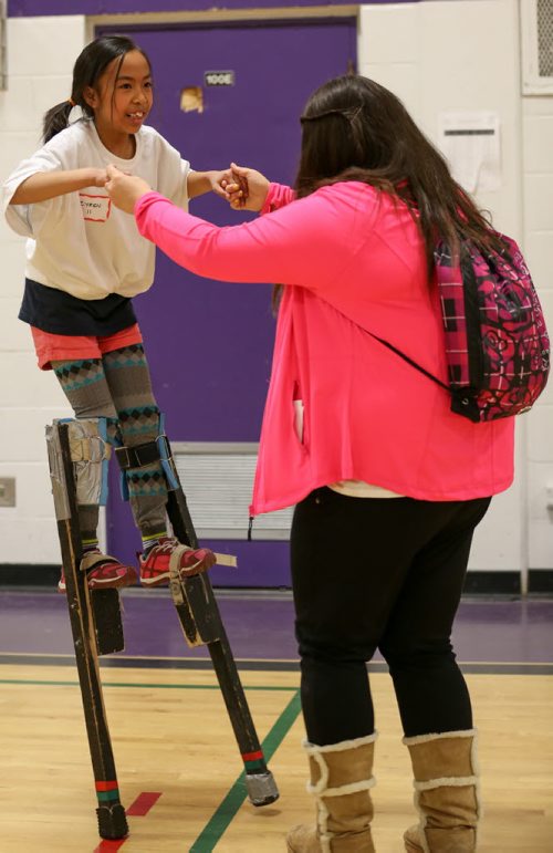 Zyren Jupiter, 9, left, learns to walk on stilts with help from volunteer, Stefanie Aguiar, at the 17th annual Circus and Magic Partnership (C.A.M.P) at Gordon Bell High School in Winnipeg on Tuesday, April 1, 2014. C.A.M.P is an artistic intervention project for at-risk kids, spearheaded by the Winnipeg International Children's Festival . (Photo by Crystal Schick/Winnipeg Free Press)