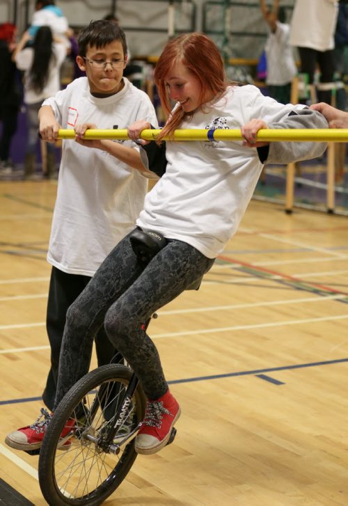 Sierra Syrnyk, 11, right, learns to ride the unicycle with the assistance of, Nickolas Garcia, 11, at the 17th annual Circus and Magic Partnership (C.A.M.P) at Gordon Bell High School in Winnipeg on Tuesday, April 1, 2014. C.A.M.P is an artistic intervention project for at-risk kids, spearheaded by the Winnipeg International Children's Festival . (Photo by Crystal Schick/Winnipeg Free Press)