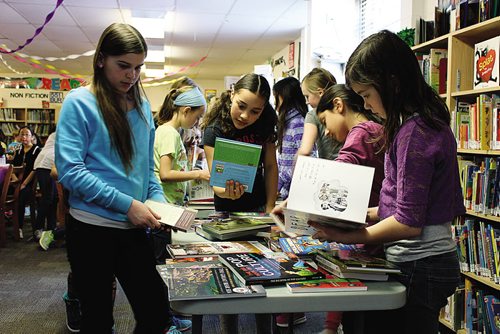 Canstar Community News (31/03/2014)- From girl on left, Hailey Peters, Th¾©a Funk, and Jillian Birdsbill are students in the Manitoba Young Readers Choice Awards club at St. Avila School. The students each read at least five books out of 18 to help contribute to voting for the 2014 MYRCA winner. (STEPHCROSIER/CANSTAR)
