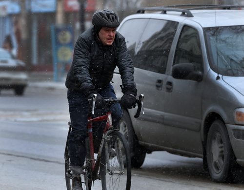 STDUP Äì Snow Will Fall . Snow is beginning to fall in downtown Winnipeg . Cyclist on Portage Ave. contends with light snow . April 3 2014 / KEN GIGLIOTTI / WINNIPEG FREE PRESS