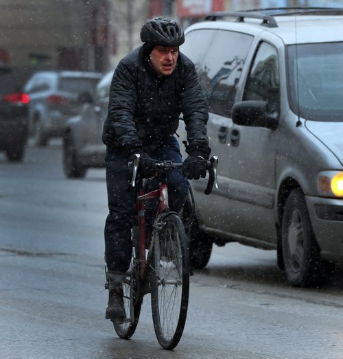 Stdup Snow Will Fall -STDUP Äì Snow is beginning to fall in downtown Winnipeg . Cyclist on Portage Ave. contends with light snow . April 3 2014 / KEN GIGLIOTTI / WINNIPEG FREE PRESS