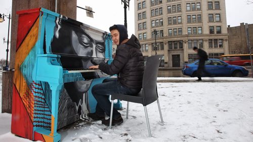 Alisher Bizhanov originally from Kazakhstan really wanted to play the piano despite the lightly falling snow Thursday afternoon outside the RRC building on Main Street.  140403 April 03, 2014 Mike Deal / Winnipeg Free Press