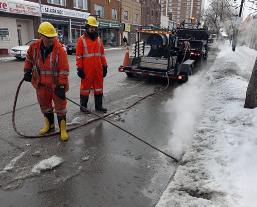 Stdup .Wpg City workers use steam to clear catch basins along Selkirk Ave to allow melted snow  to drain from city streets April 4 2014 / KEN GIGLIOTTI / WINNIPEG FREE PRESS