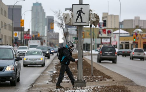 A man crosses a busy street near downtown in Winnipeg on Friday, April 4, 2014. (Photo by Crystal Schick/Winnipeg Free Press)