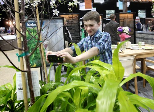 Twelve year old Matthew Trudeau takes pictures of a plant display at the Home Expression Show at the Convention Centre Saturday in hopes of planting a garden with his mom this spring.  Standup photo  April 05,  2014 Ruth Bonneville / Winnipeg Free Press