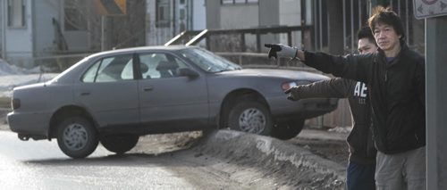 While waiting for a tow, Freddie Kwok at right and his son Fred alert traffic on an icy curve on Broadway near Portage Ave. that resulted in Fred's car sliding over the curb. Wayne Glowacki / Winnipeg Free Press April 11   2014